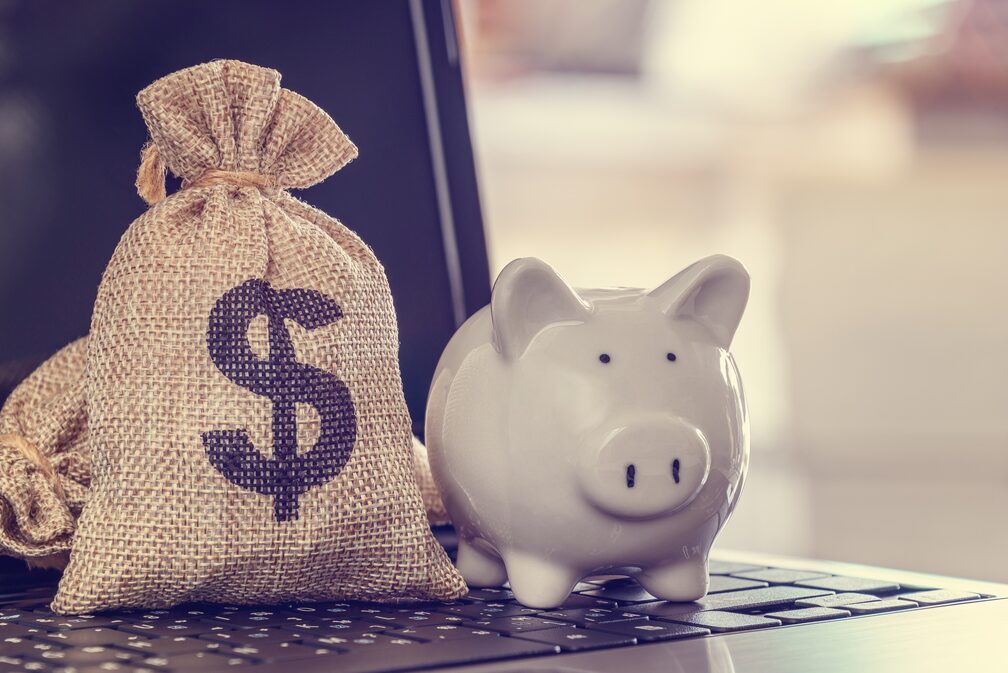 piggy bank and sack of cash on a laptop computer keyboard