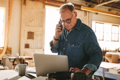 mature small businessman on phone and computer