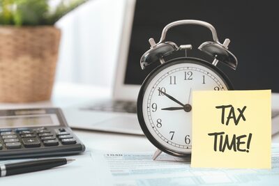 Sticky note with the words Tax Time stuck to alarm clock