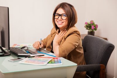 Smiling young bookkeeper at desk with reports and computer